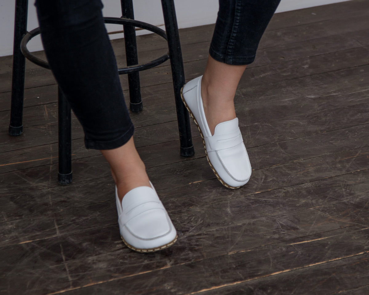 Kadın beyaz Atkılı barefoot ayakkabı, tabureye otururken yandan görünüm